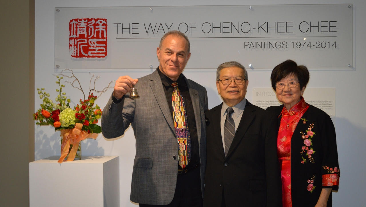 Ken Bloom holding a bell while posing for a photo opportunity with artist Cheng-Khee Chee and his spouse Sing-Bee Chee