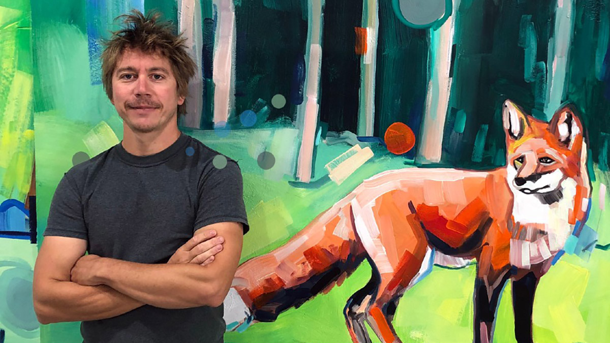 Artist Adam Swanson standing with armed crossed in front of his painting of a fox