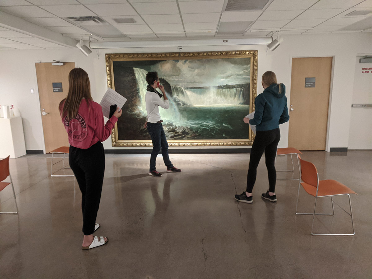 three students standing in front of a large Gilbert Munger painting of the Niagara Falls