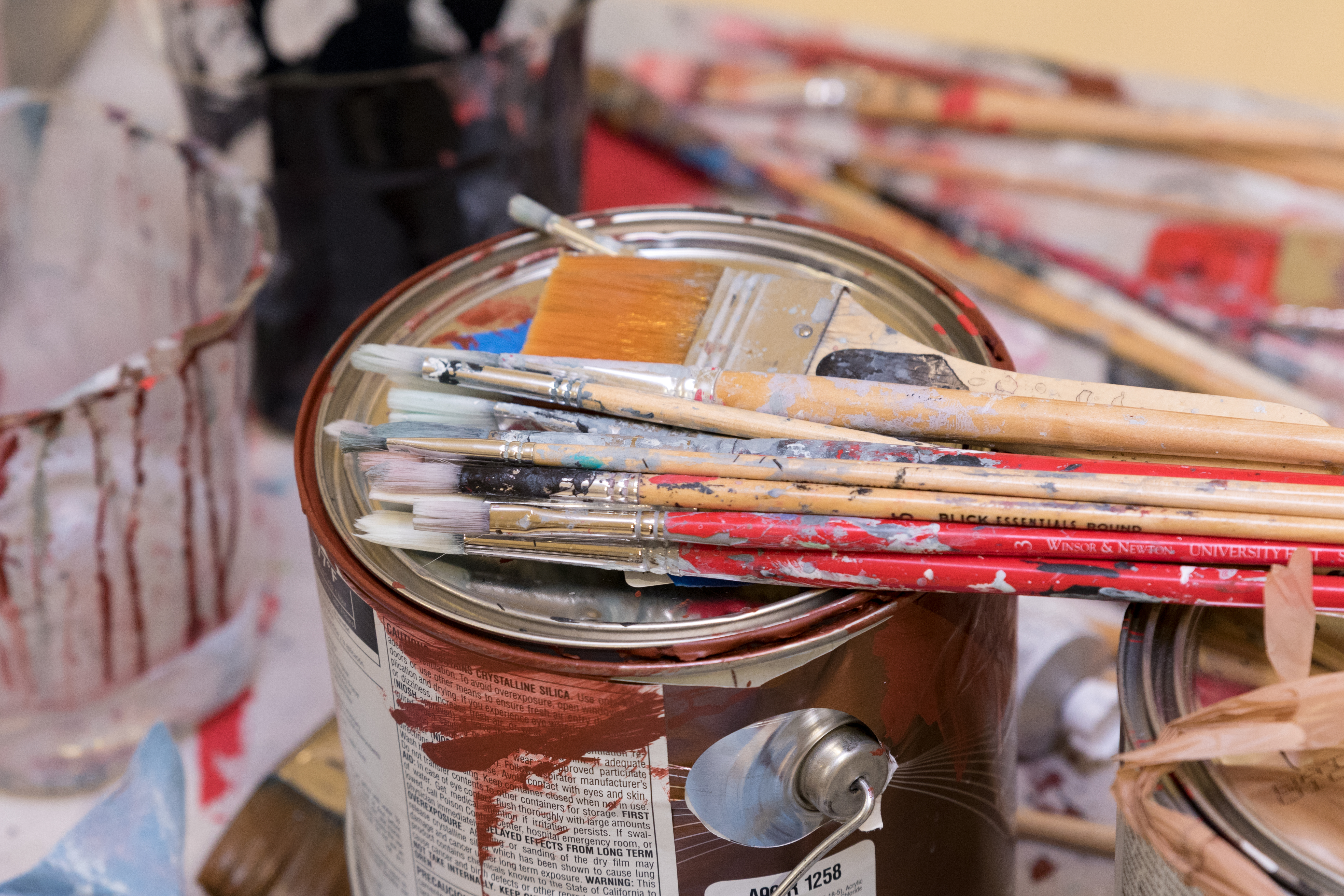 photo of a can of paint covered with paint brushes