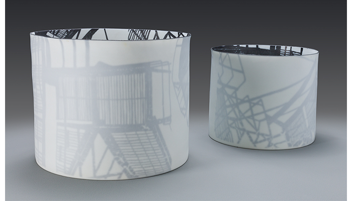 two glass cylindrical vessels with a black and white design on the interior surface