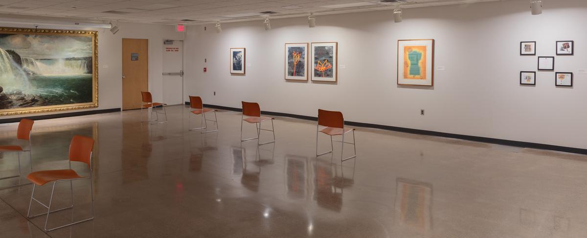 An art gallery with chairs arranged facing the pieces of art on the walls.