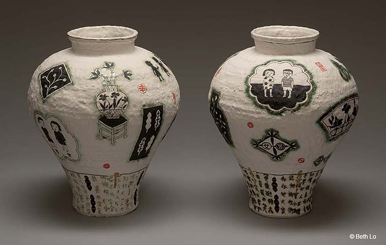 Two paper vases with designs painted on them in black.